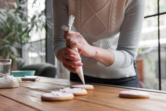Woman decorating cookies with a pastry bag full of icing 