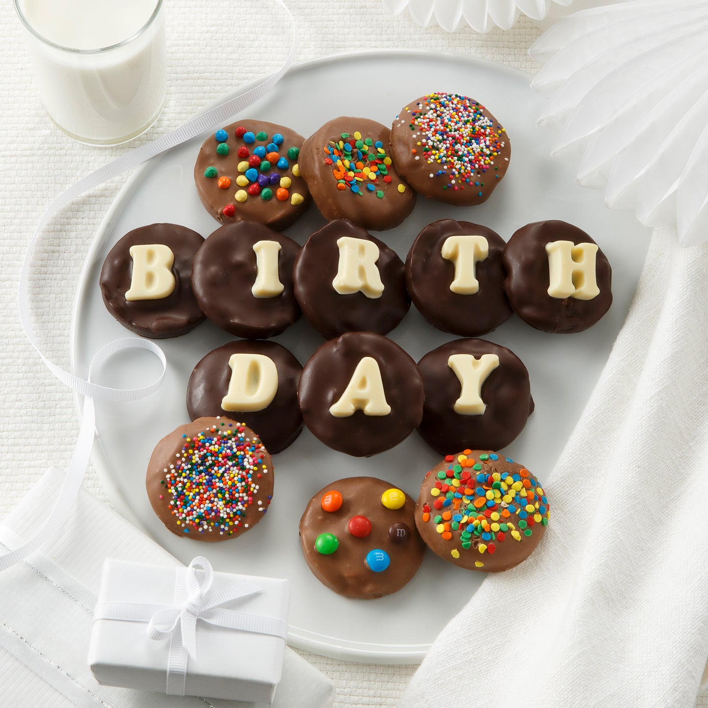 A plate of Nibblers bite-sized cookies covered in dark and milk chocolate, decorated with sprinkles and 'Birthday' spelled out on them in white chocolate molds.
