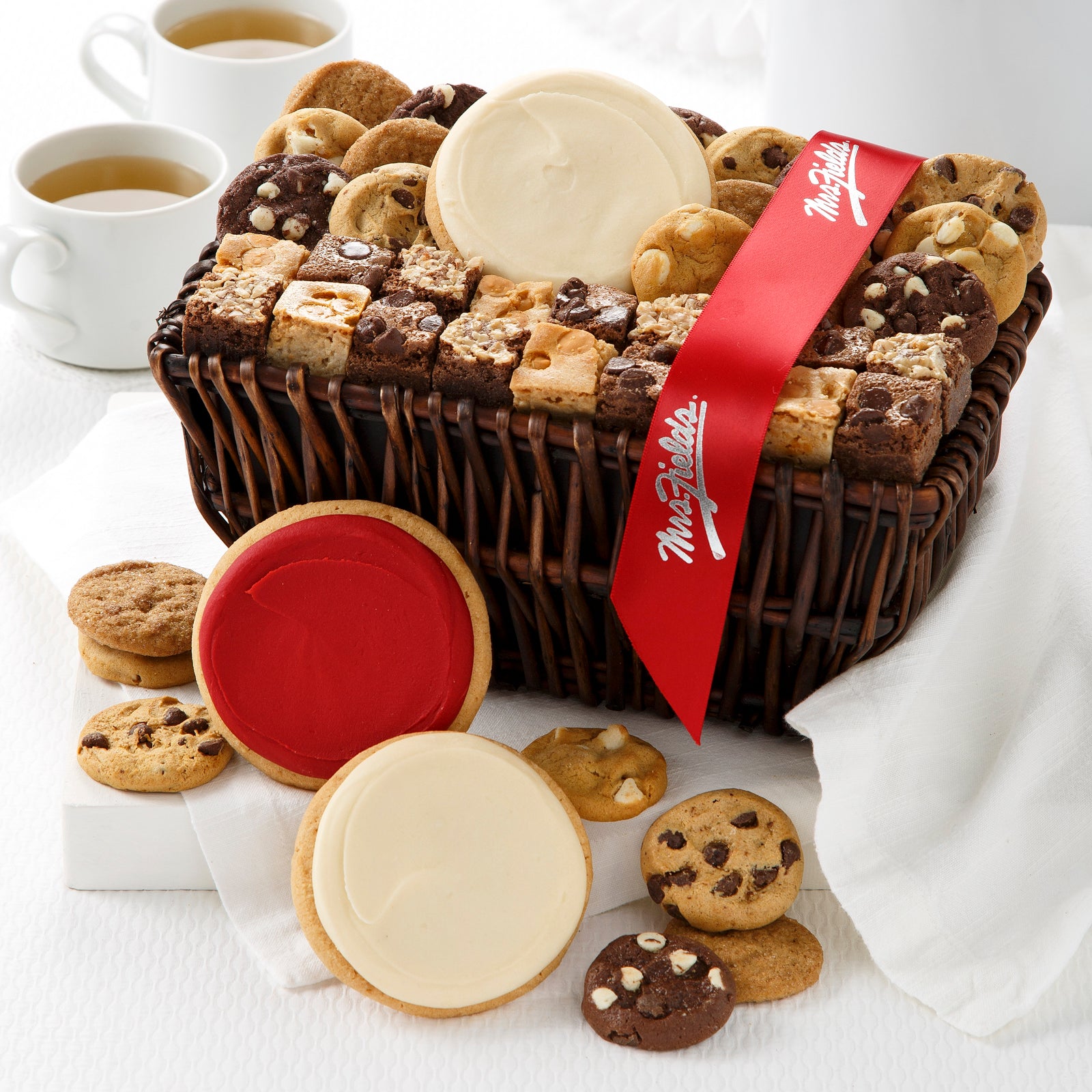 Brown gift basket filled with an assortment of nibblers, brownie bites, and frosted cookies