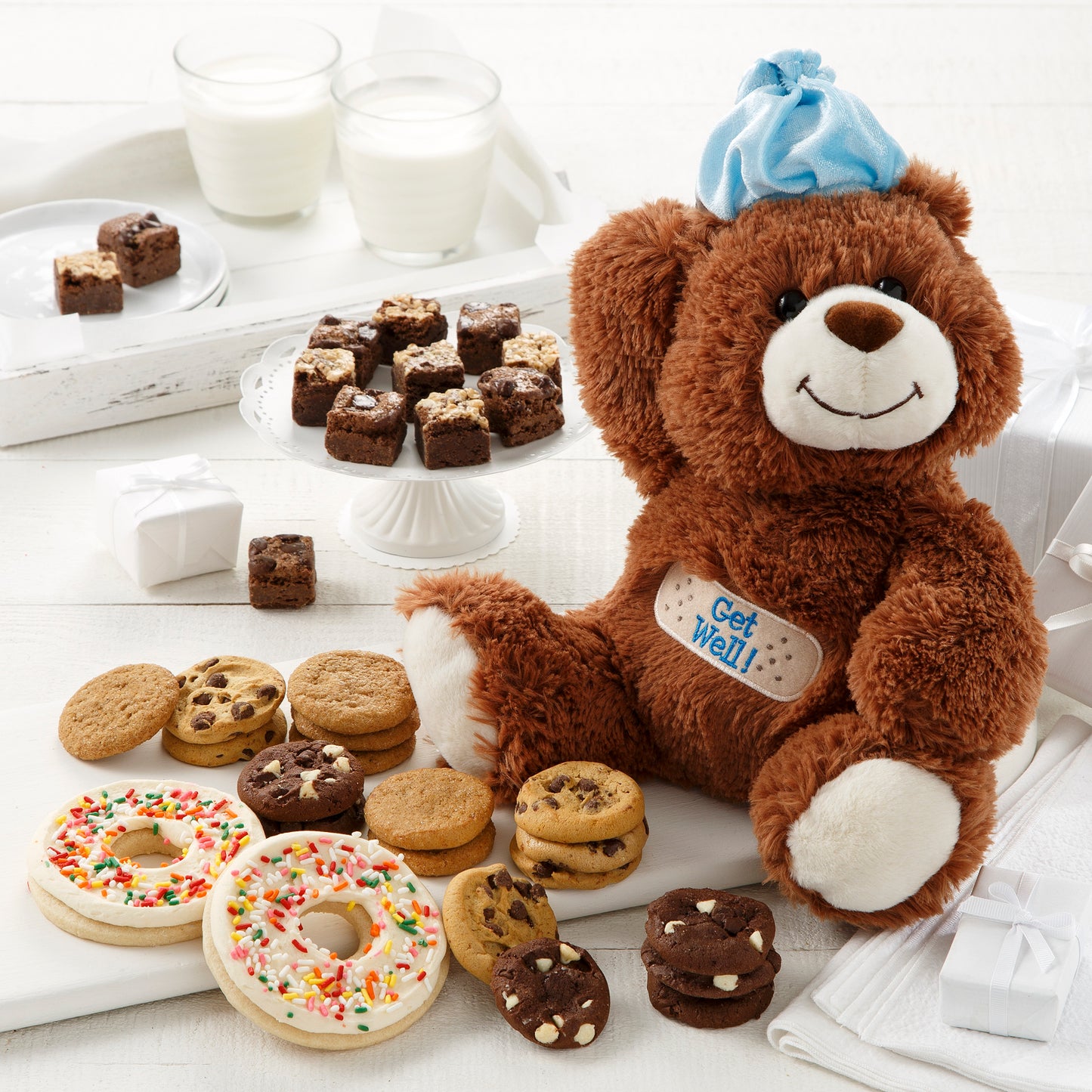 A stuffed Get Well bear surrounded by an assortment of nibblers, brownie bites, and frosted donut cookies with sprinkles
