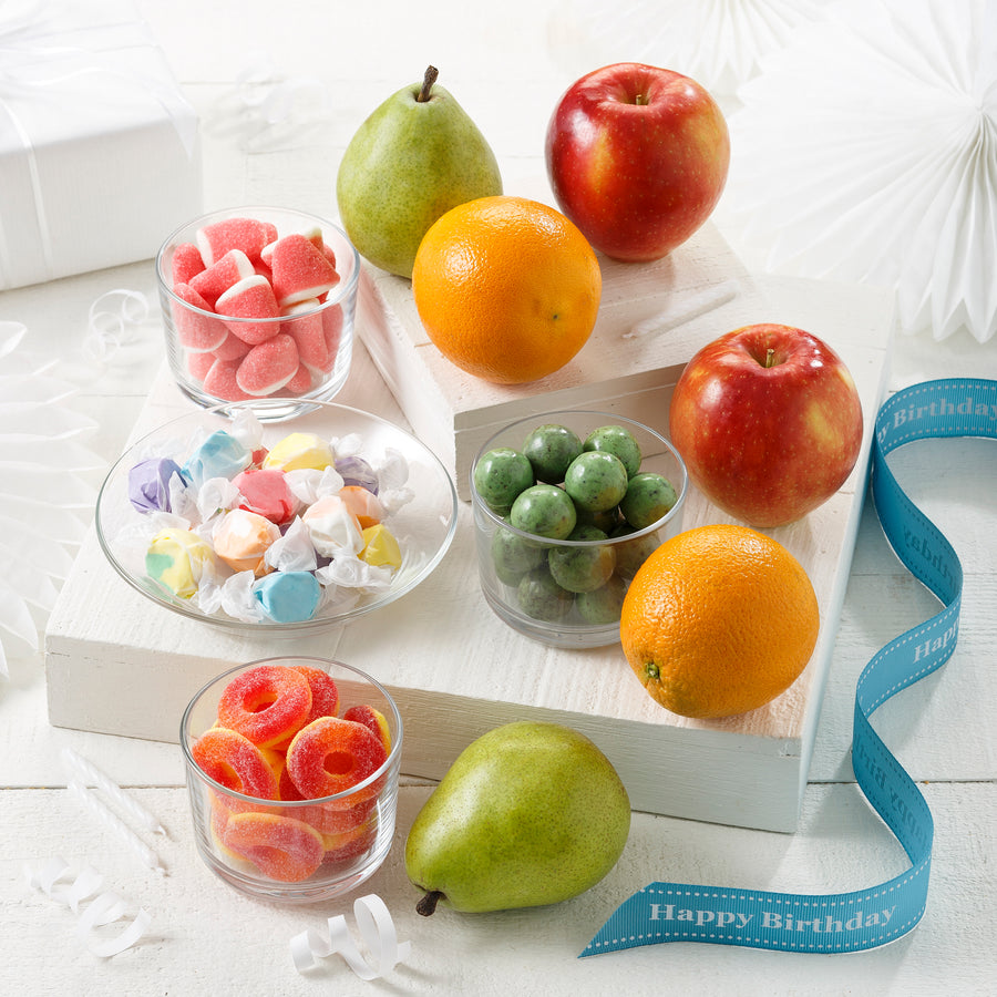 Two apples, two oranges, two pears, and an assortment of candies with a blue happy birthday ribbon
