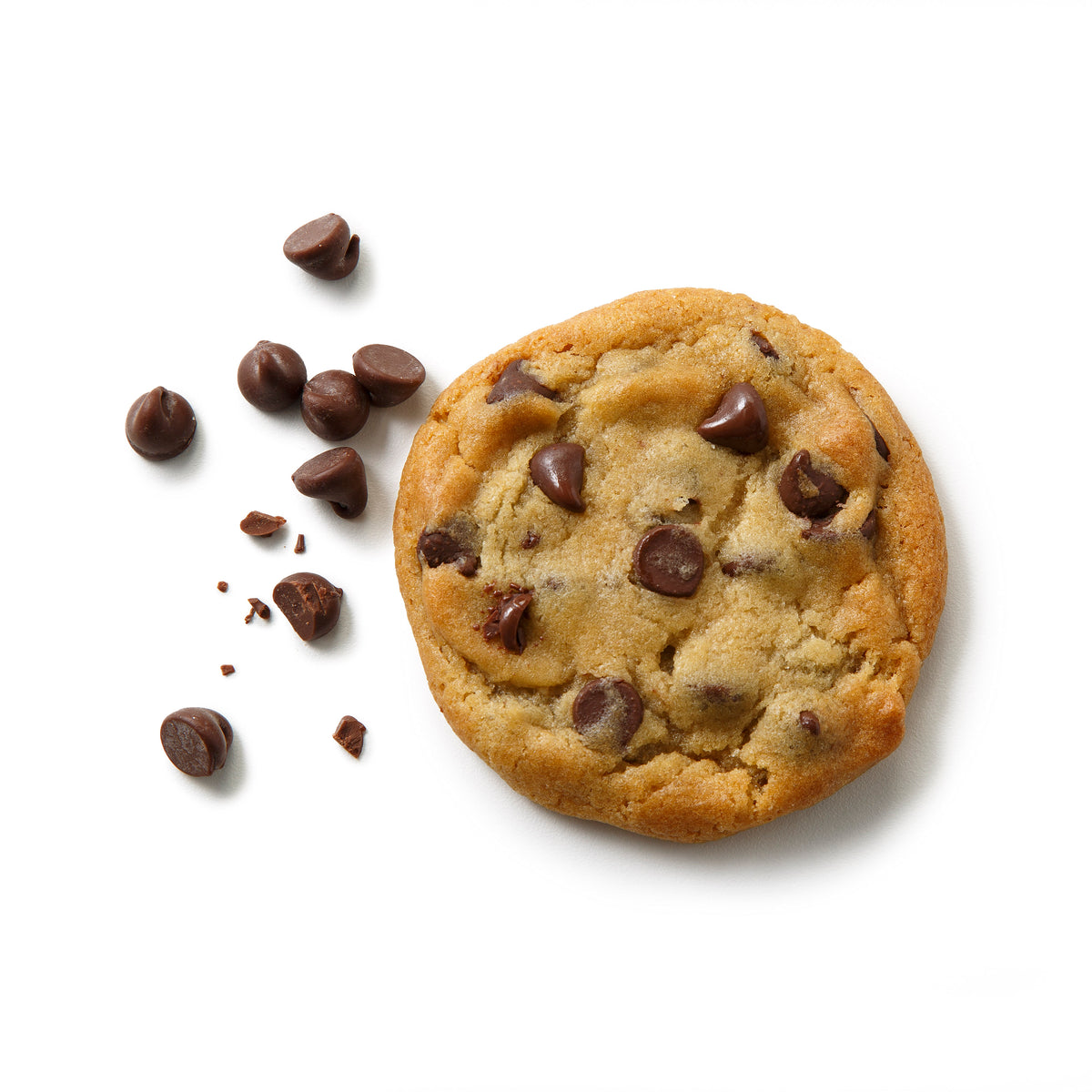 A chocolate chip cookie on a white background with several chocolate chips scattered to the left.