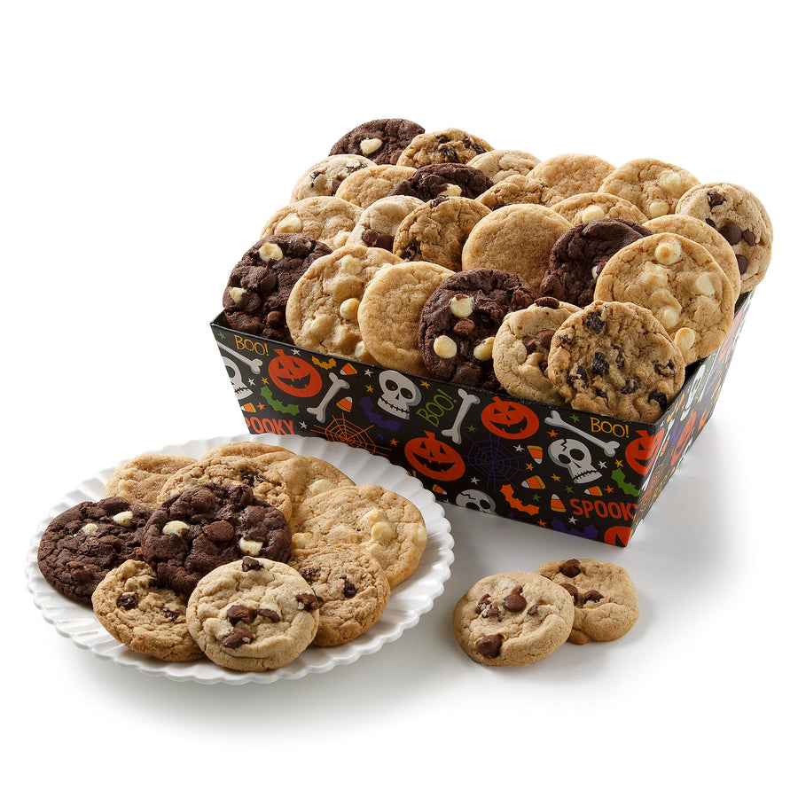 A halloween themed crate with jack-o-lanters, skeletons, and spider webs on it filled with an assortment of small cookies on a blank white surface.