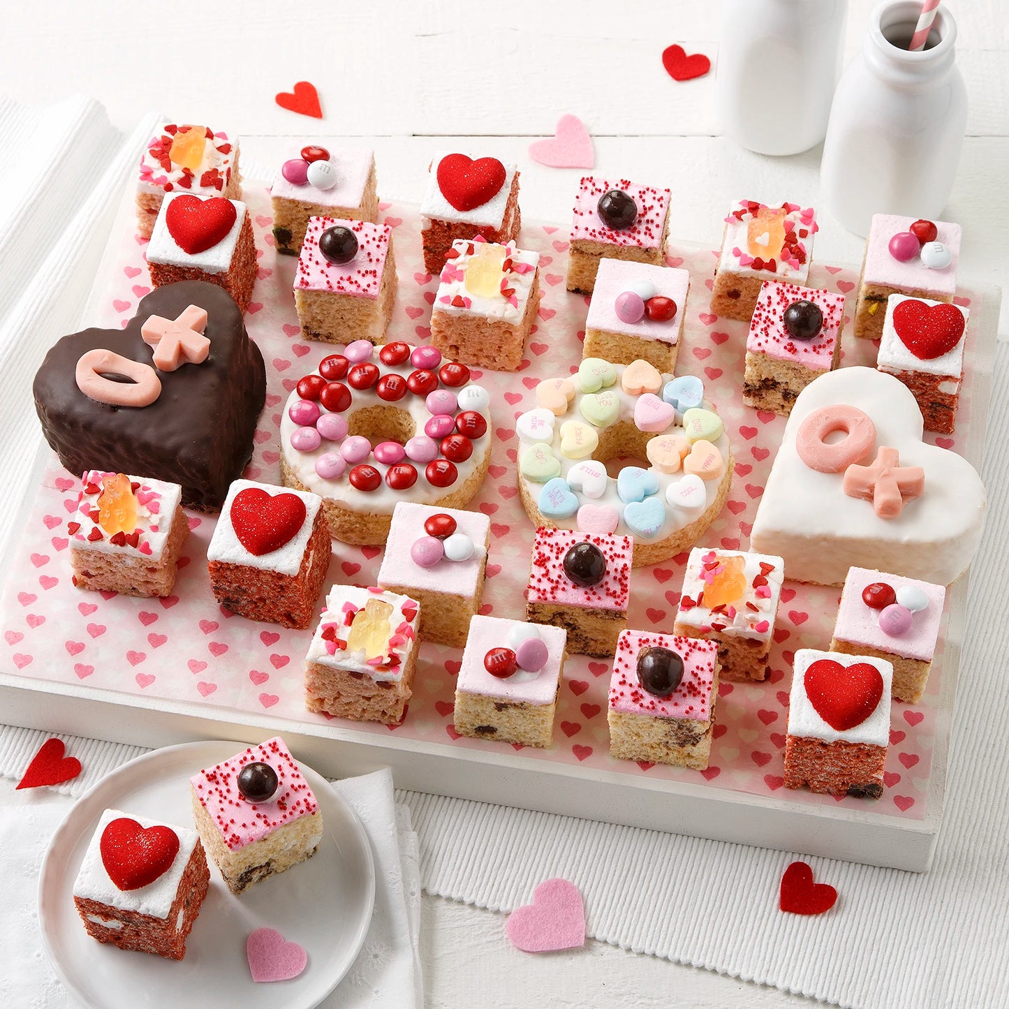 A large assortment of Valentine's Day themed rice krispie treats each uniquely decorated, including two heart shaped, chocolate-covered rice krispies and two donut shaped rice krispies decorated with candy.