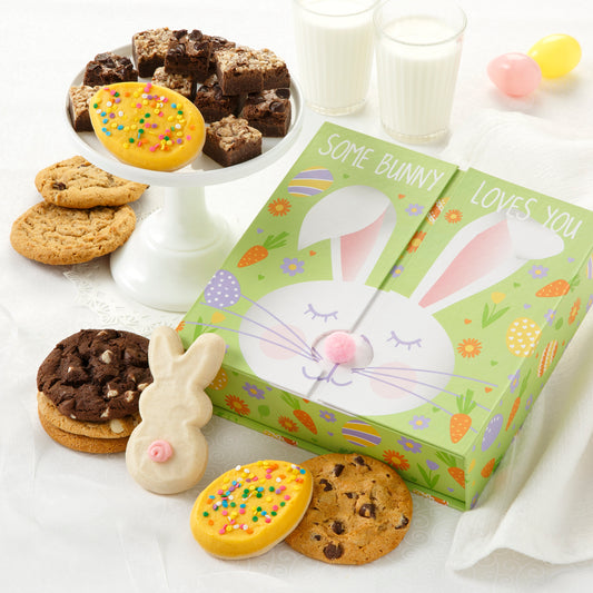 A light green gift box decorated with a bunny and surrounded by an assortment of original cookies, brownie bites, frosted egg cookies and a frosted bunny cookie