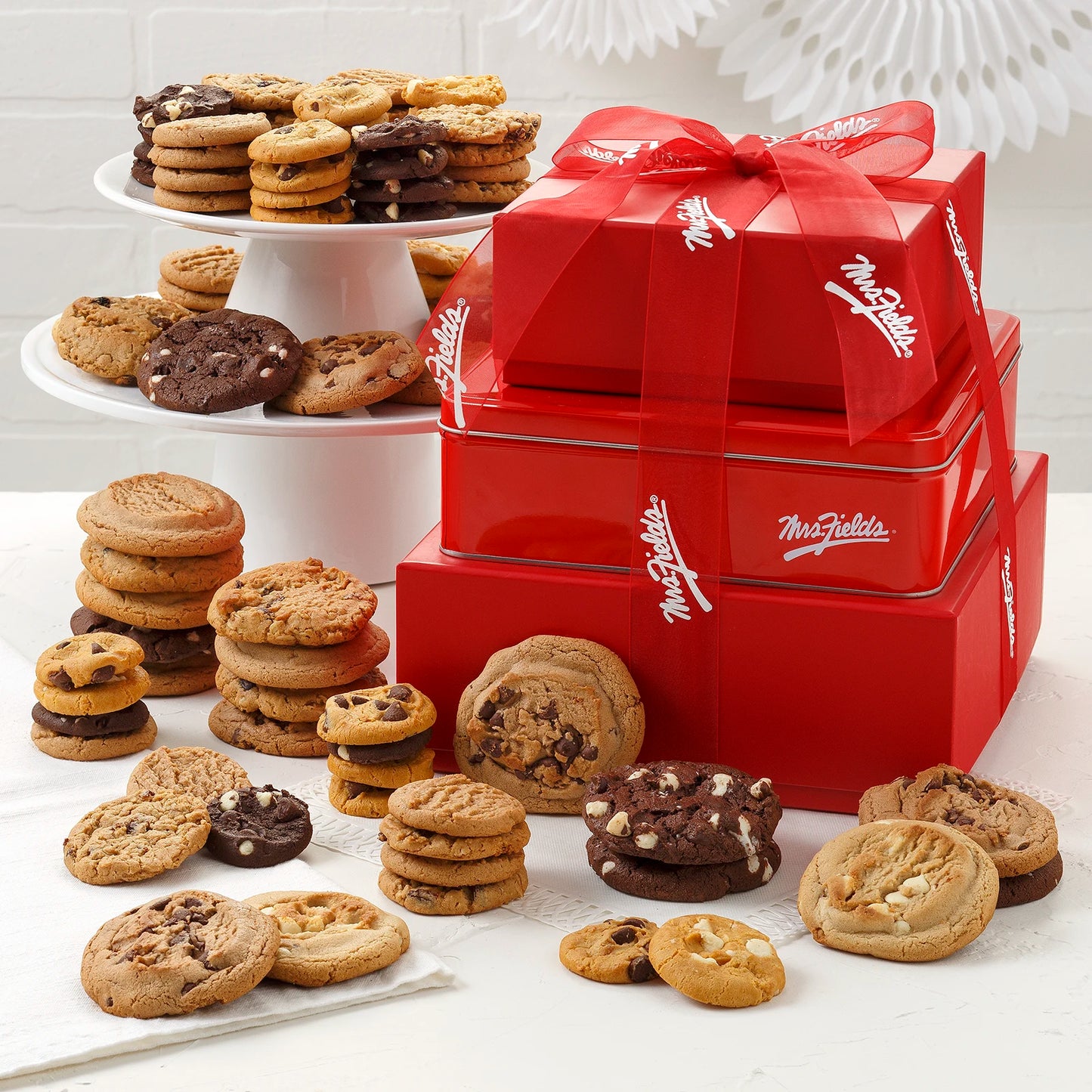 A stack of red boxes and a tin filled with original cookies and Nibblers® Bite-Sized Cookies
