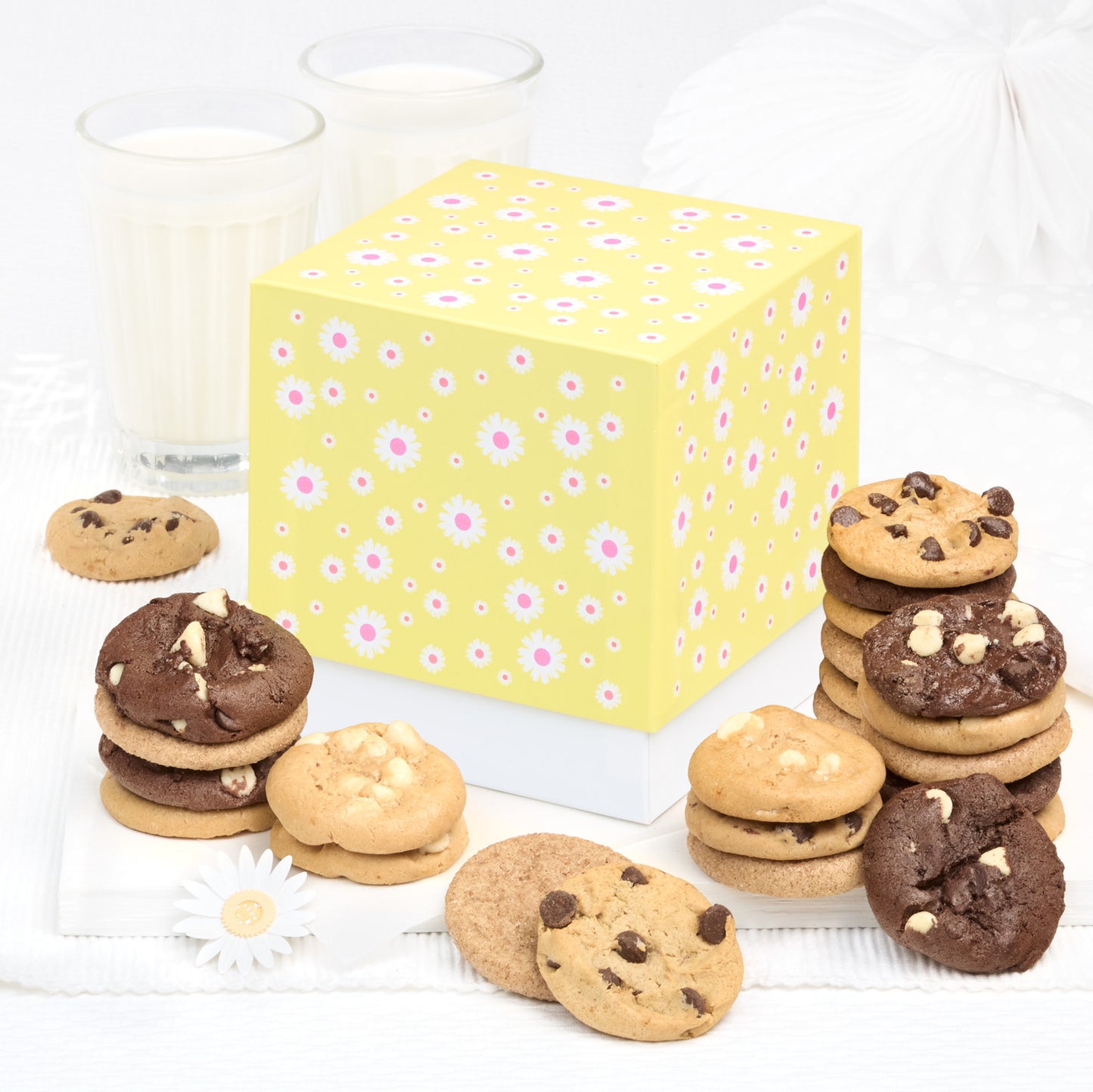 A yellow mini gift box decorated with white flowers surrounded by an assortment of nibblers