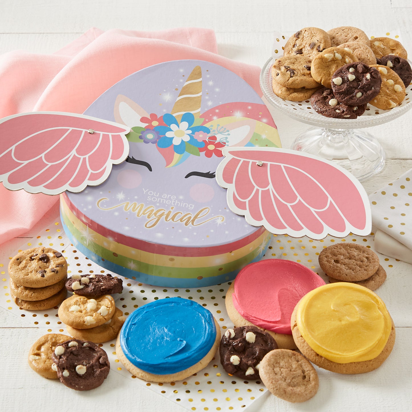 Magical Unicorn Box surrounded by an assortment of nibblers and frosted round cookies