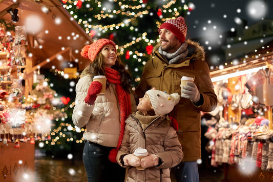 Happy family enjoying Christmas activities at a market while drinking hot chocolate