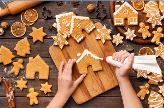 Woman decorating gingerbread cookies with white icing 