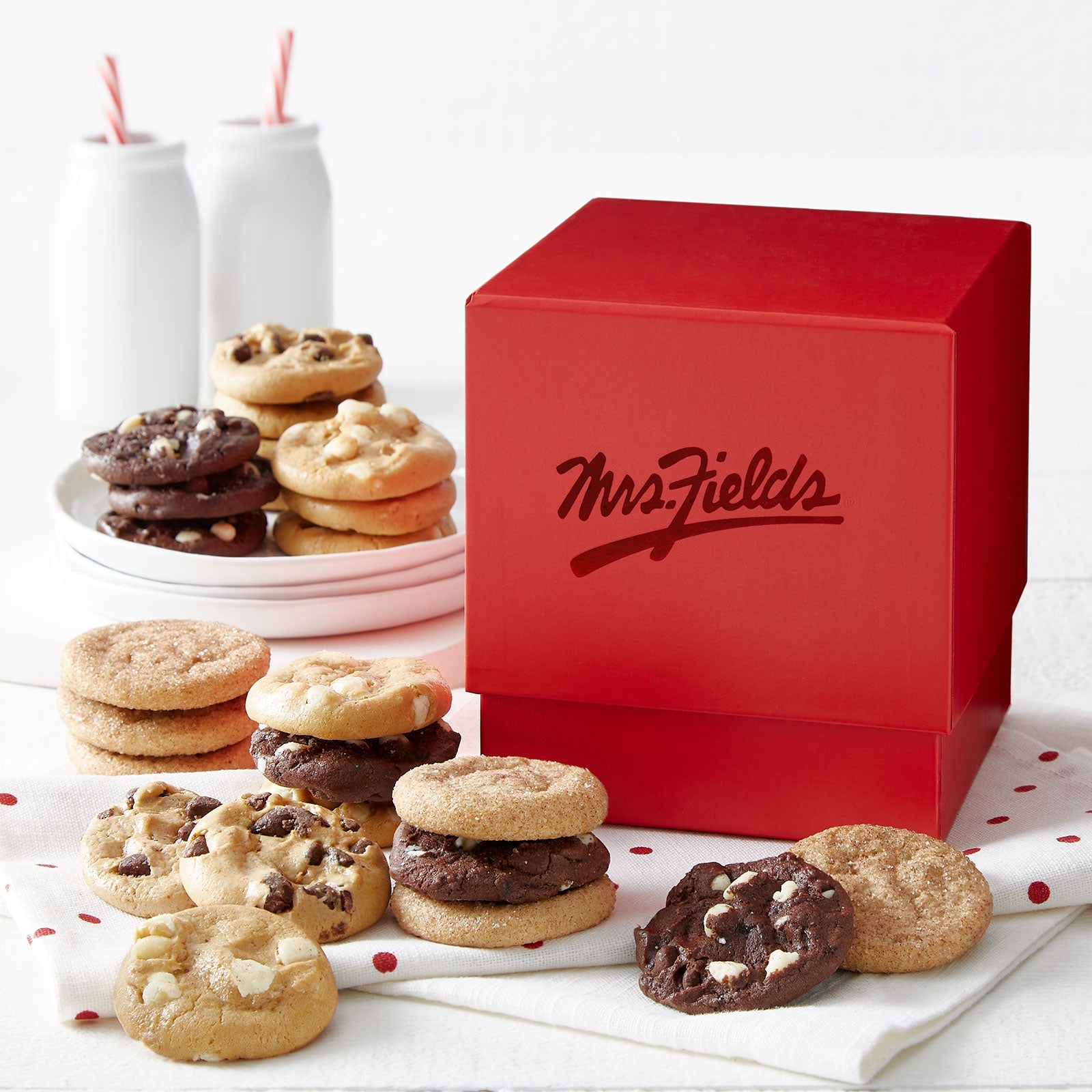 A red mini Mrs. Fields gift box surrounded by an assortment of nibblers