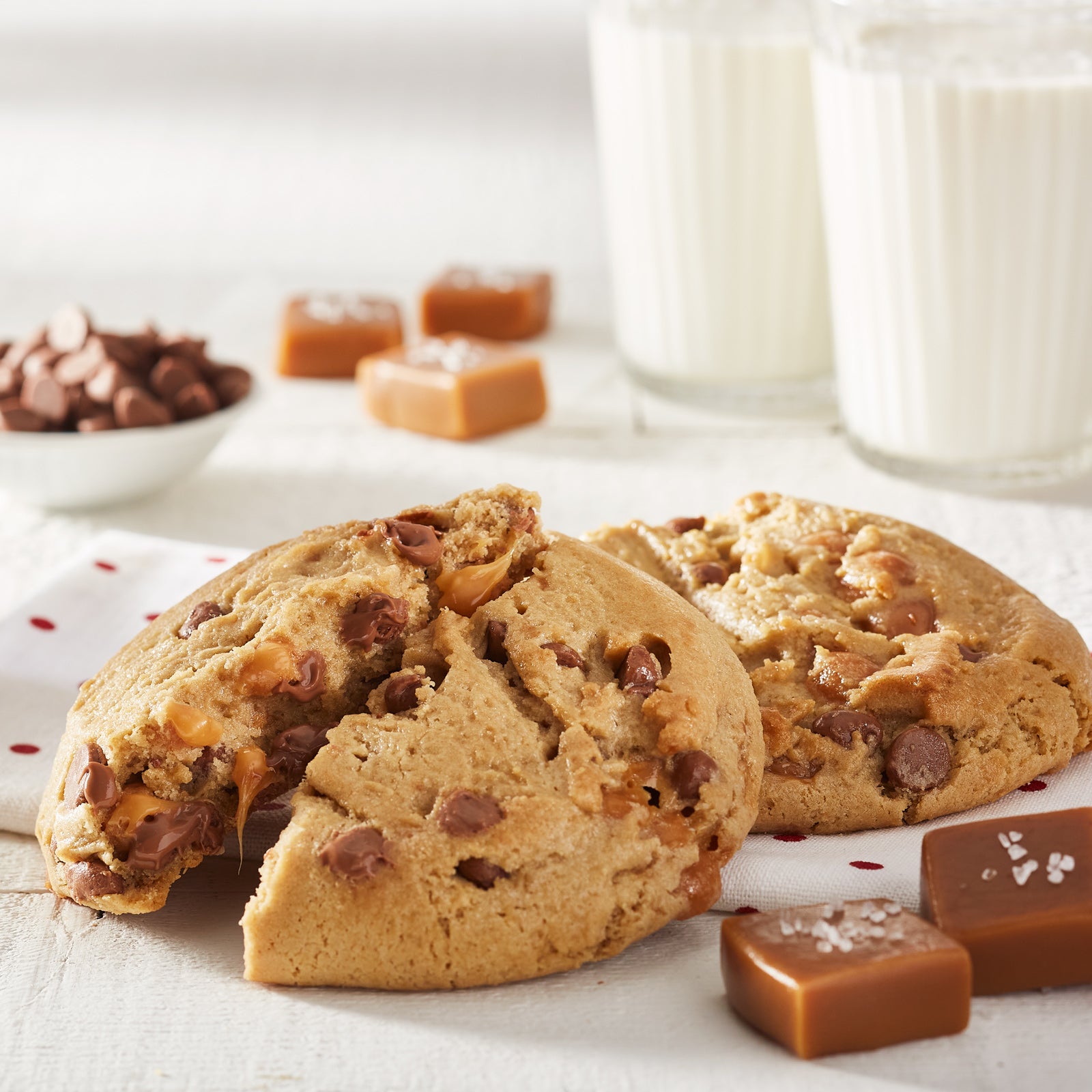 Salted caramel mega cookie broken in half with pieces of caramel surrounding the cookie