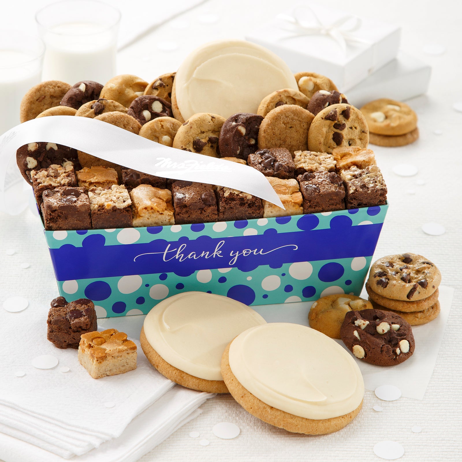 A blue polka dot Thank You gift crate filled with an assortment of nibblers, brownie bites, and frosted white round cookies