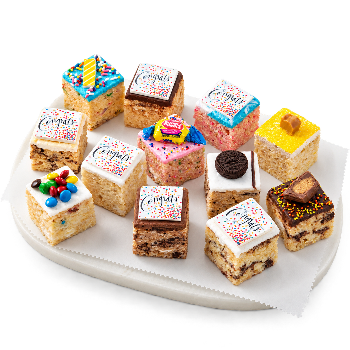 A set of ten assorted rice cake treats decorated like mini cupcakes, arranged on a white scalloped serving platter. The treats feature various colorful frosting tops, sprinkles, and some are labeled 'Congrats'.