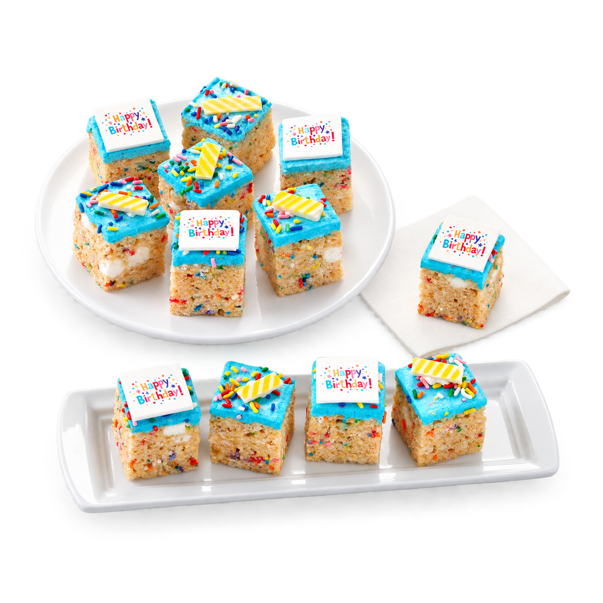 Nine square rice cake slices decorated with bright blue frosting, sprinkles, and a white 'Happy Birthday!' sign, arranged on two white serving platters against a clean white background.