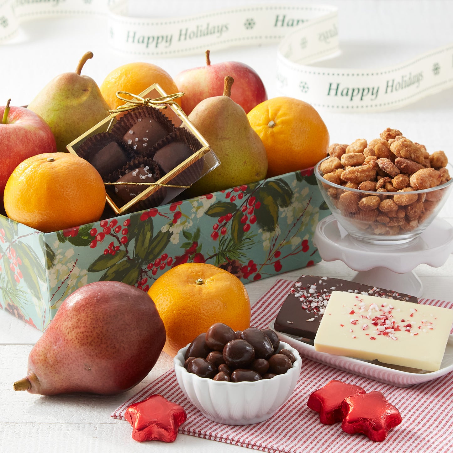A decorated holiday crate filled with an assortment of fruit, nuts, and chocolate.