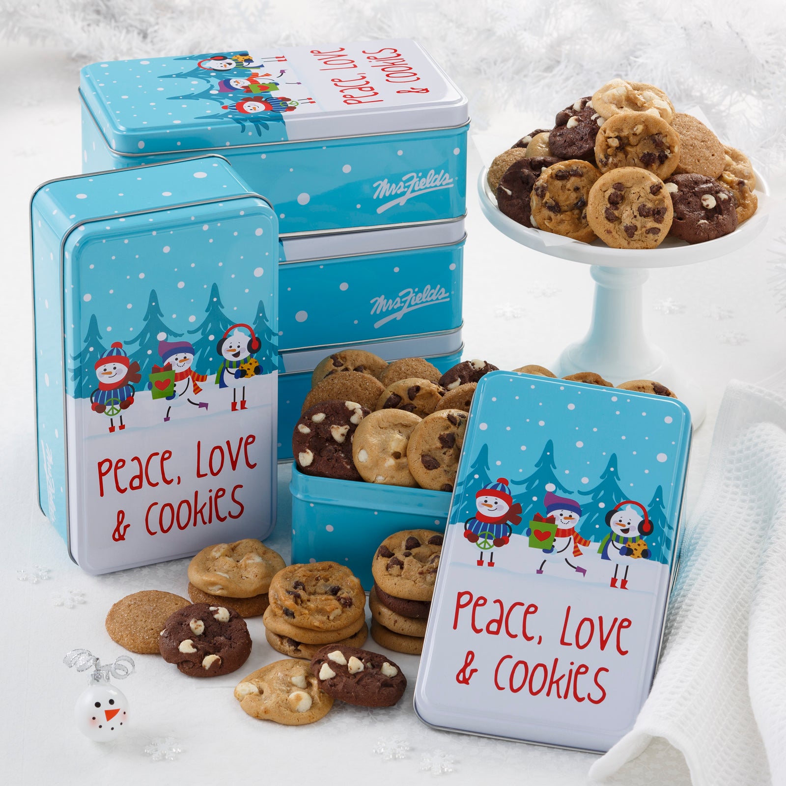 Five tins of Peace, Love and Cookies sentiment on gift tins with snowman friends as decorations. This tin is filled with an assortment of Nibblers®