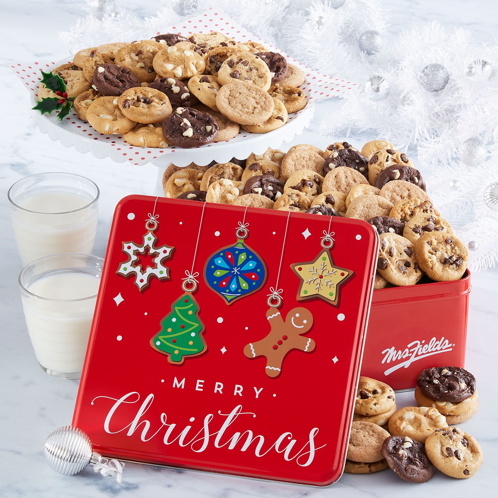 A red tin with a Merry Christmas sentiment decorated with ornaments and filled with an assortment of Nibblers®.