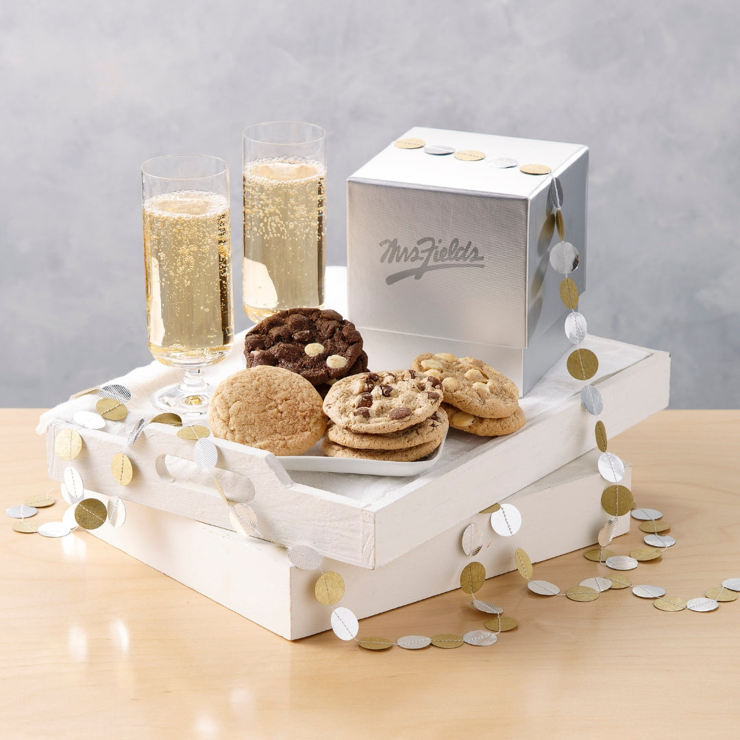 A gift set on a light wood table featuring a white wooden box, a silver Mr. & Mrs.