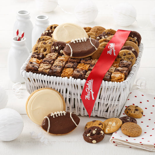 A white basket filed with Nibblers®, brownie bites, two frosted white round cookies, and two frosted football cookies