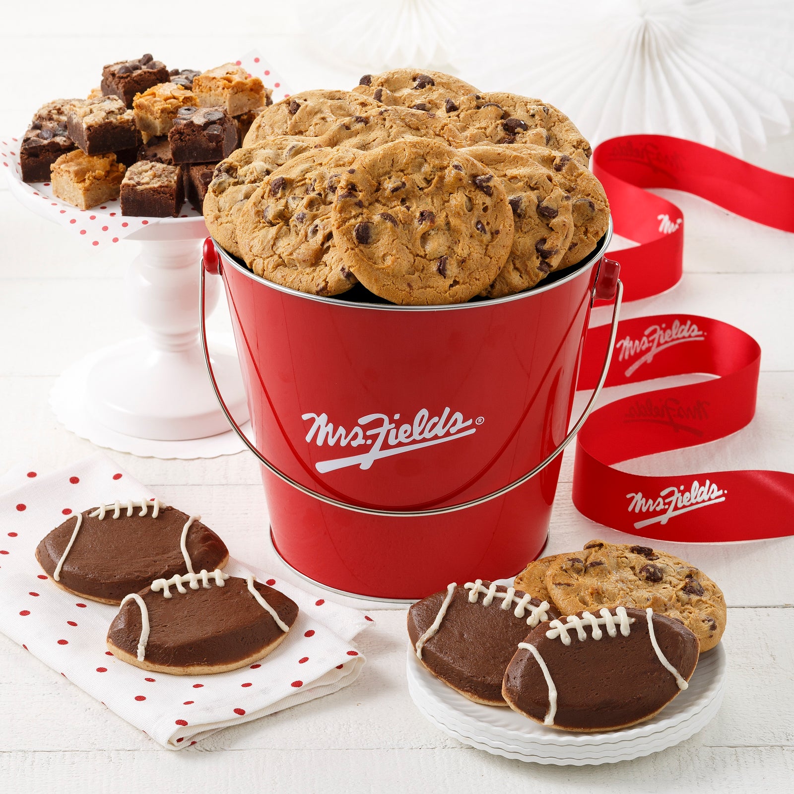 A signature Mrs. Fields pail filled with 12 semi-sweet chocolate chip original cookies, an assortment of brownie bites, and four frosted football cookies