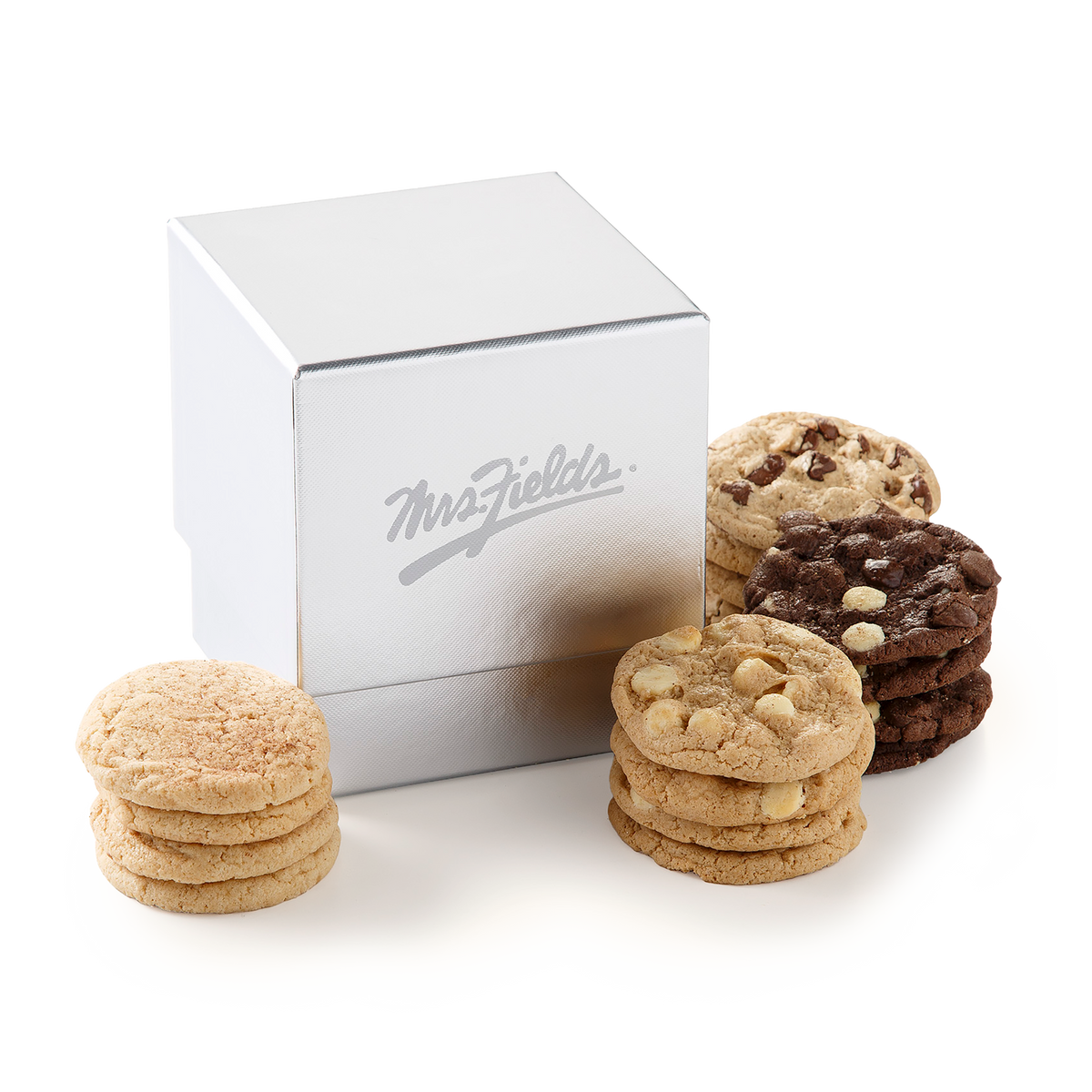 A silver square gift box with the Mrs. Fields logo on the front, surrounded by stacks of assorted cookies including chocolate chip and white chocolate chip cookies on a white background.