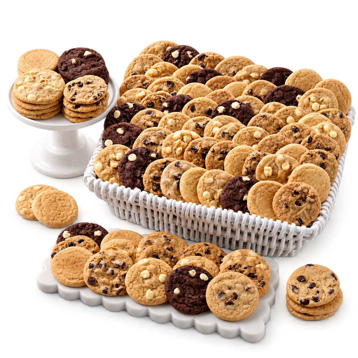 An assortment of cookies displayed on a white pedestal, a white basket, and a white scalloped serving platter on a clean white background. The cookies include chocolate chip cookies, oatmeal cookie clusters, and dark chocolate cookies.