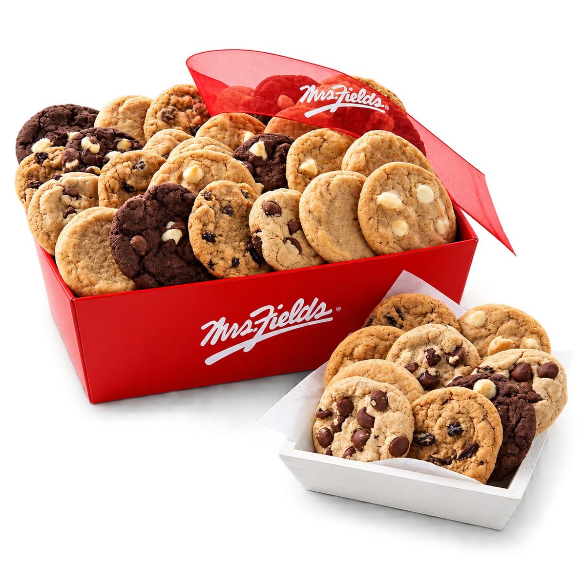 A red gift box of Mrs. Fields assorted cookies with a red ribbon, shown alongside a white tray of chocolate chip and white chocolate chip cookies on a clean white background.