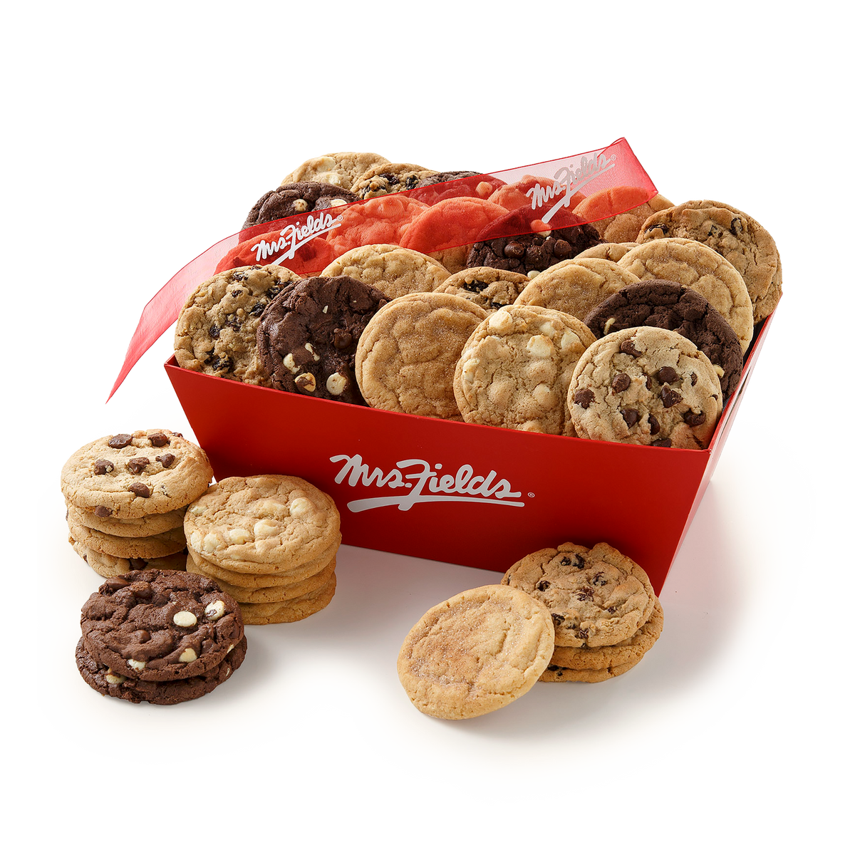 A red Mrs. Fields cookie box filled with assorted chocolate chip cookies, with several stacks of cookies placed in front on a clean white background.