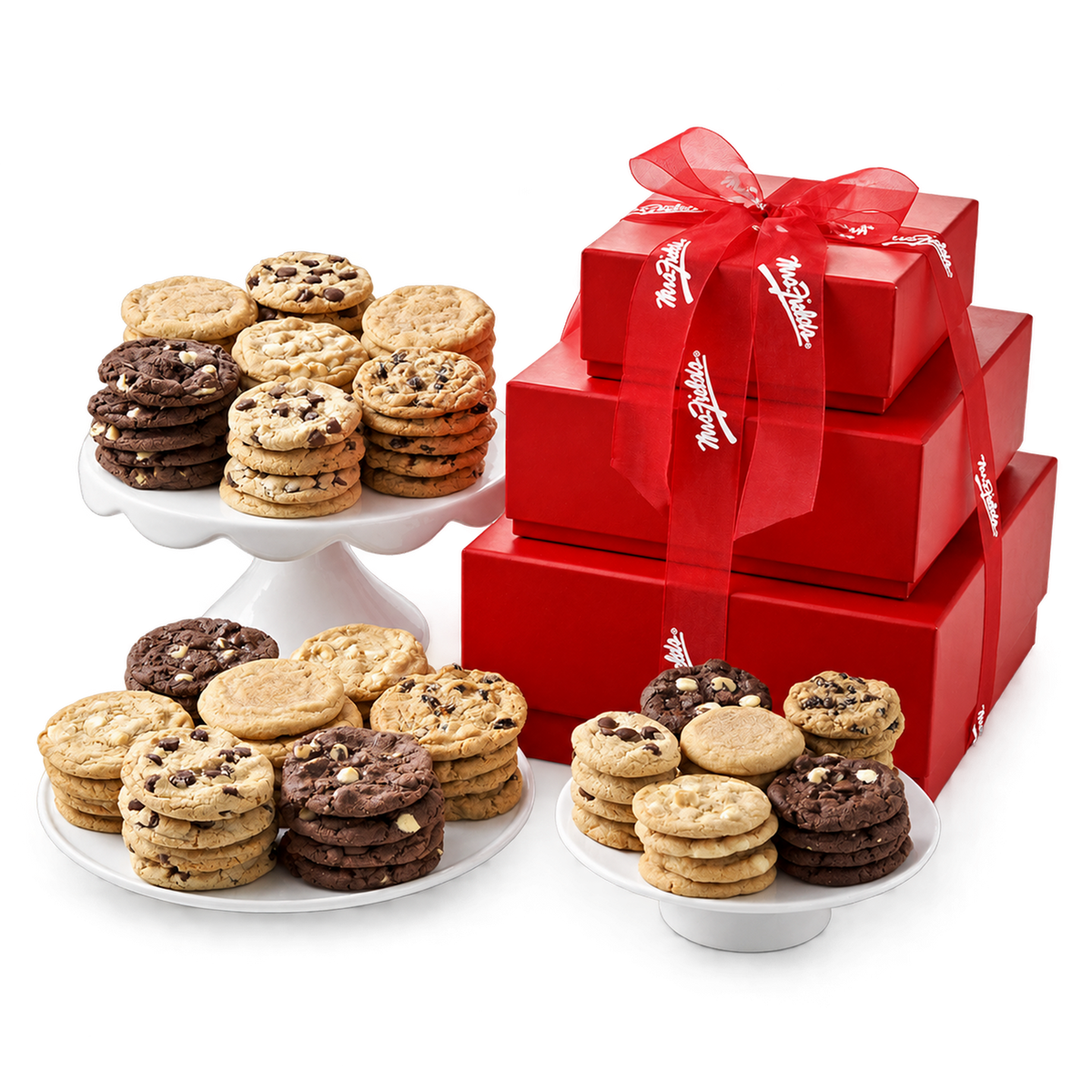 A gift set of cookies and red boxes on a white background. Three white pedestal stands filled with assorted cookies, including chocolate chip cookies, sugar cookie dough, and chocolate cookie dough, alongside three red gift boxes tied together with a red ribbon printed with the Mrs Fields brand name.