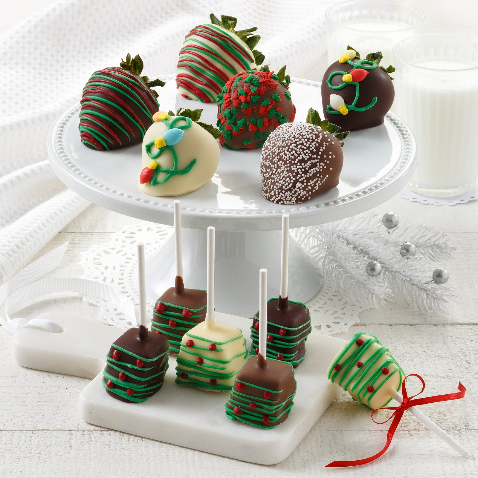 Six chocolate-covered strawberries and six chocolate covered cheesecake pops that are all decorated in a holiday theme