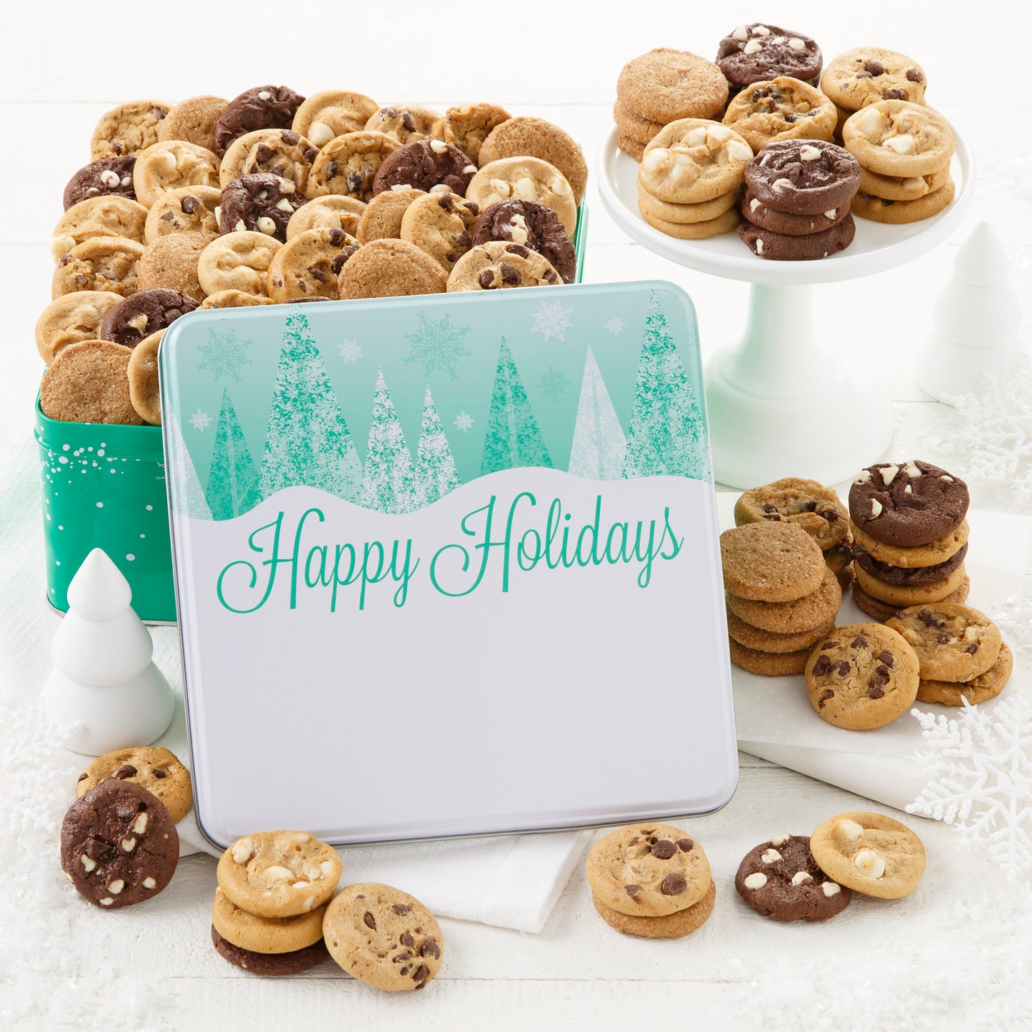 A Happy Holidays gift tin decorated with Christmas Trees and snowflakes and filled with an assortment of Nibblers®