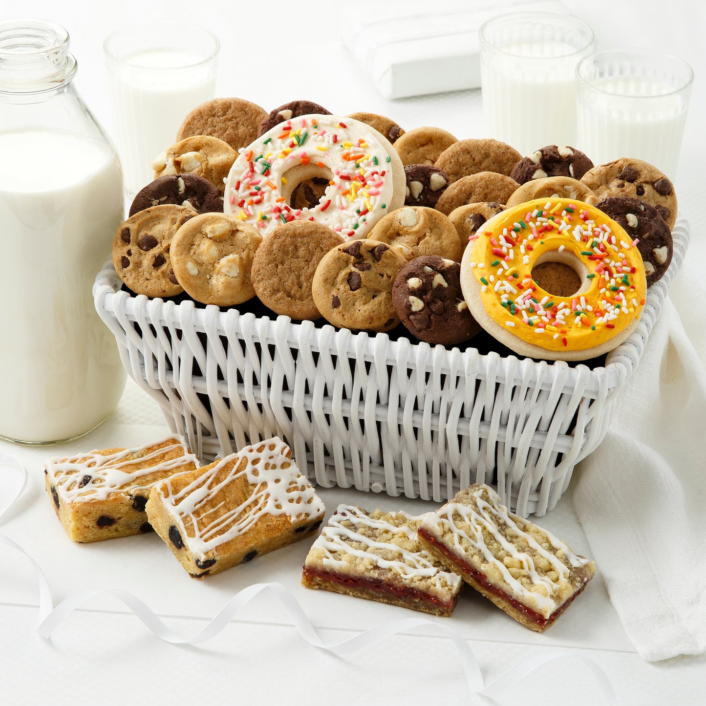 White basket filled with Nibblers® and two frosted cookies. Four assorted flavor fruit bars are placed in front