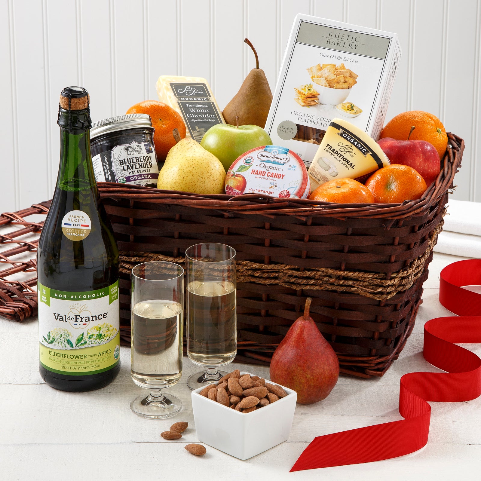 A brown gift basket filled with an assortment of fruit and snacks