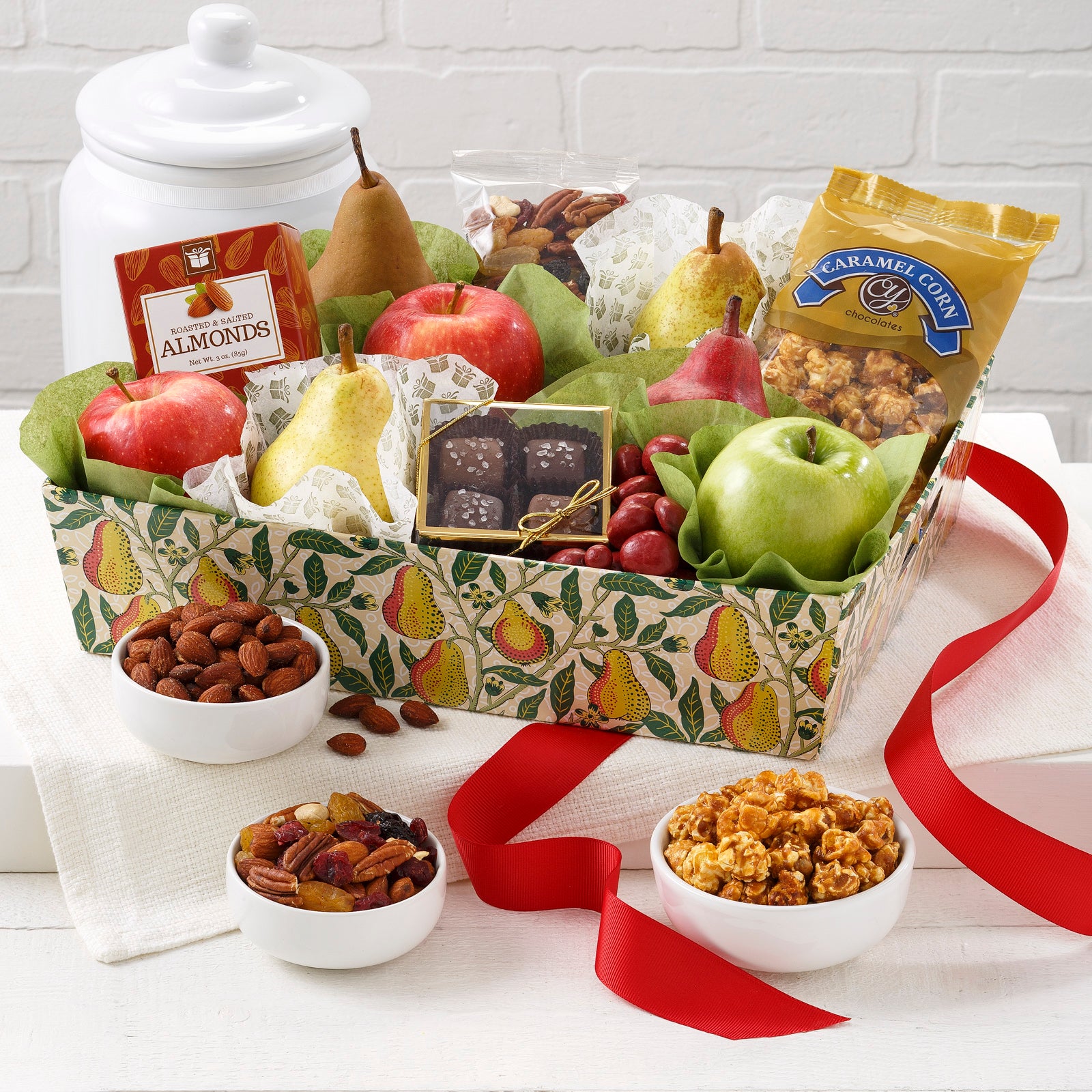 A gift basket decorated with pears and filed with an assortment of fruit and snacks