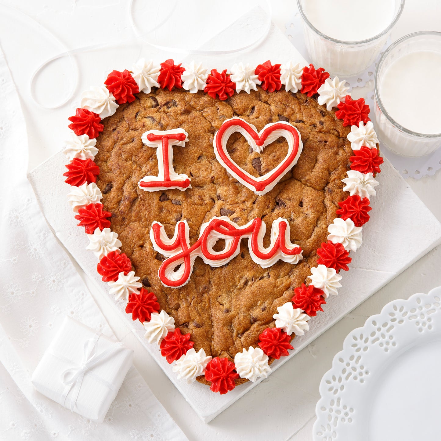 A heart-shaped cookie cake with an I Love You sentiment with red and white frosting.