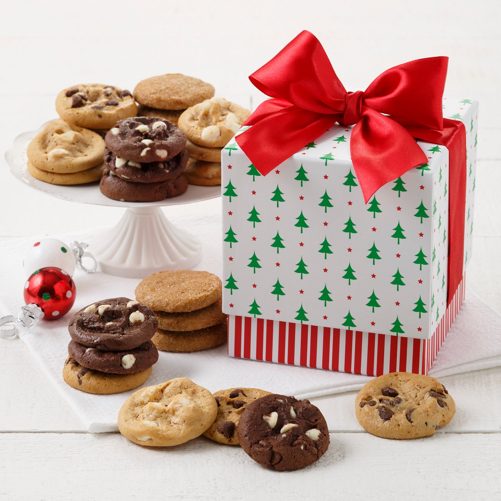 Mini gift box with a Christmas trees on the top and a red and white striped base. There is an assortment of Nibblers® surrounding the gift box