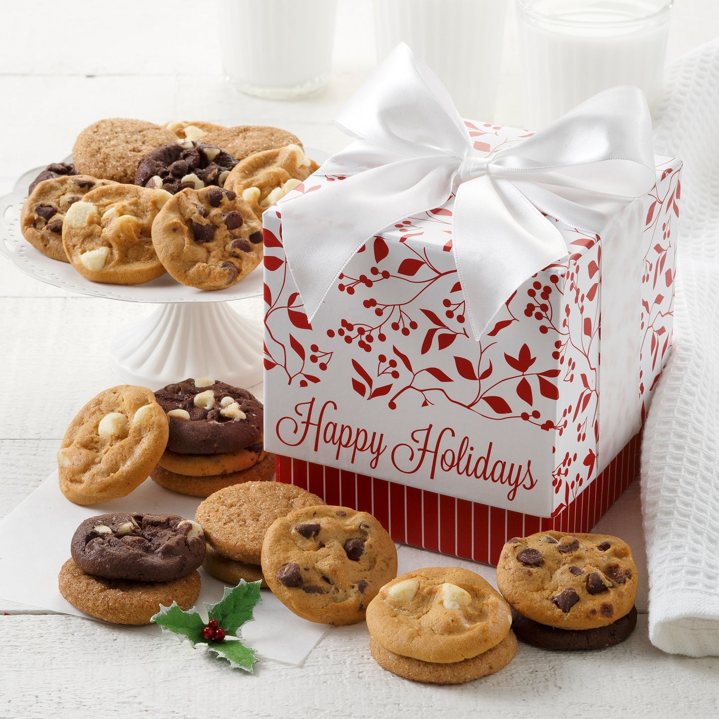 A Happy Holidays mini gift box decorated with holly and surrounded by an assortment of Nibblers®