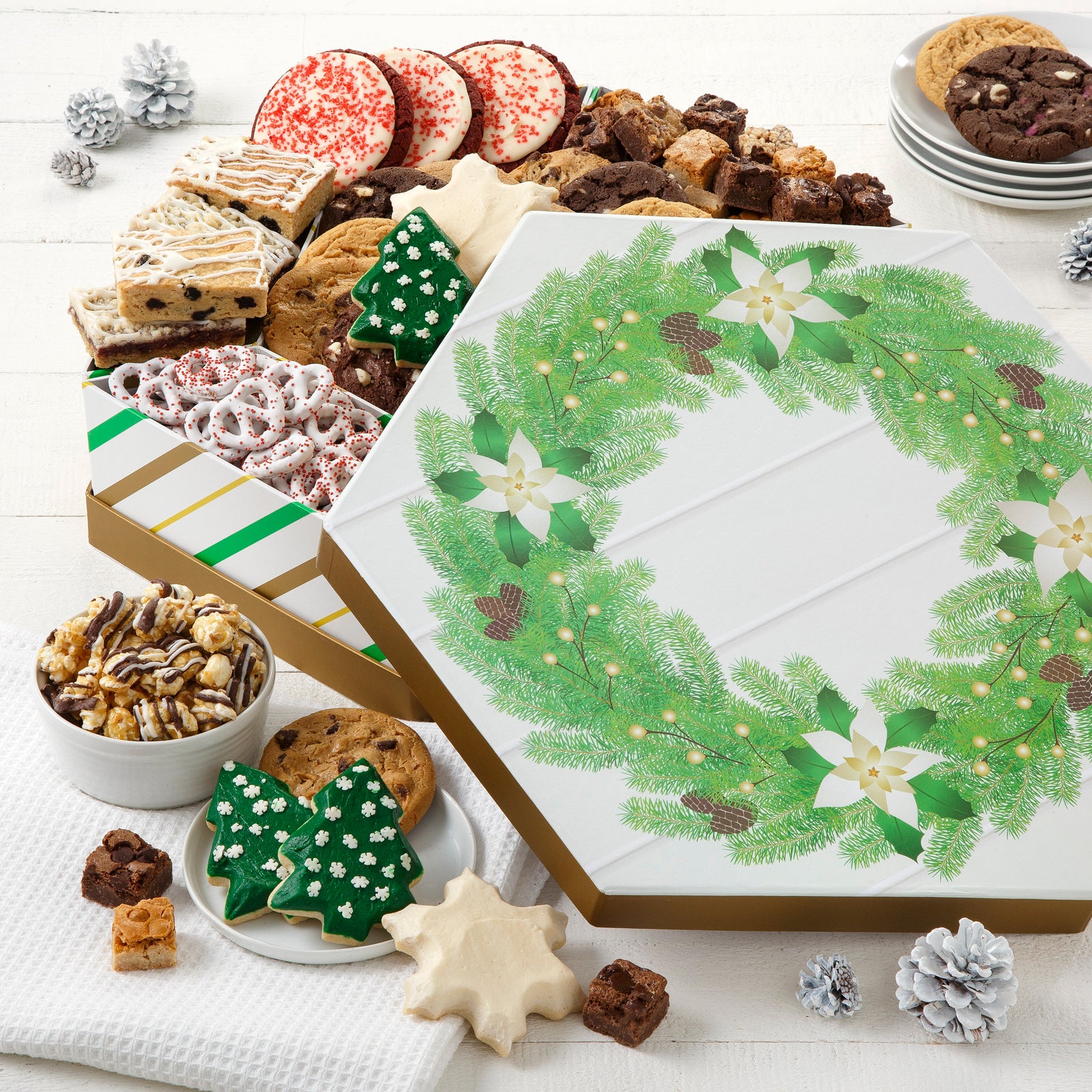 A gift box decorated with a festive wreath and filled with an assortment of holiday treats