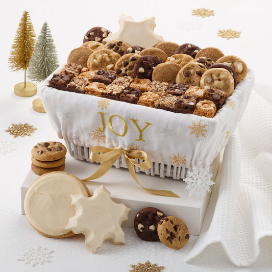 A basket decorated with a sentiment of Joy and covered with gold stars and filled with an assortment of Nibblers®, brownie bites, one frosted round cookie, and one frosted snowflake cookie. 