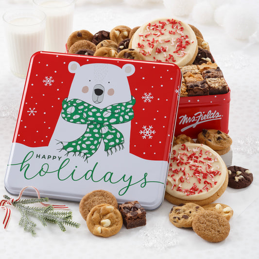 A Happy Holiday tin decorated with a polar bear filled with Nibblers®, brownie bites, and two frosted peppermint round cookies with sprinkles. 