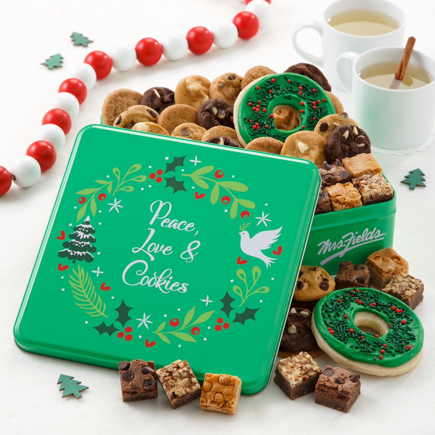 Green Peace, Love & Cookies decorated with a holiday wreath and filled with Nibblers®, brownie bites, and two frosted wreath cookies with sprinkles.