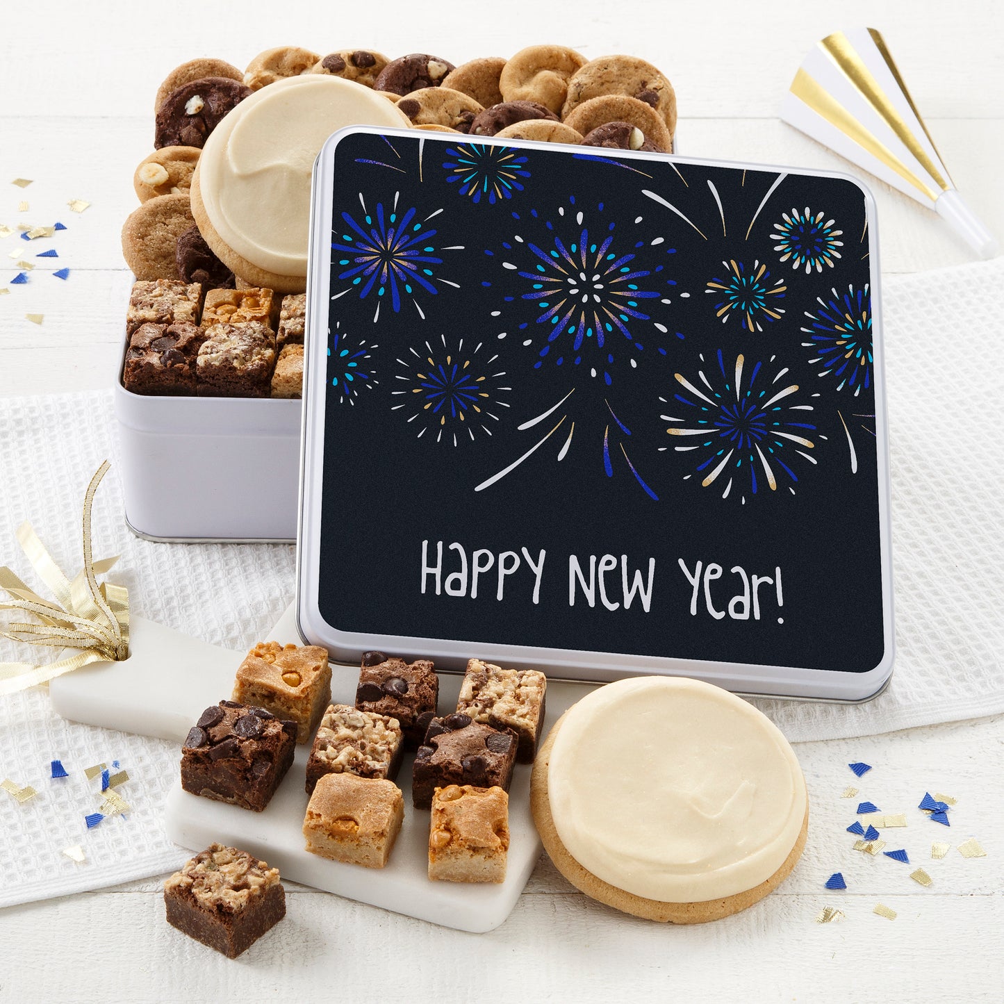 A Happy New Year gift tin filled with an assortment of Nibblers, brownie bites, and two frosted round cookies