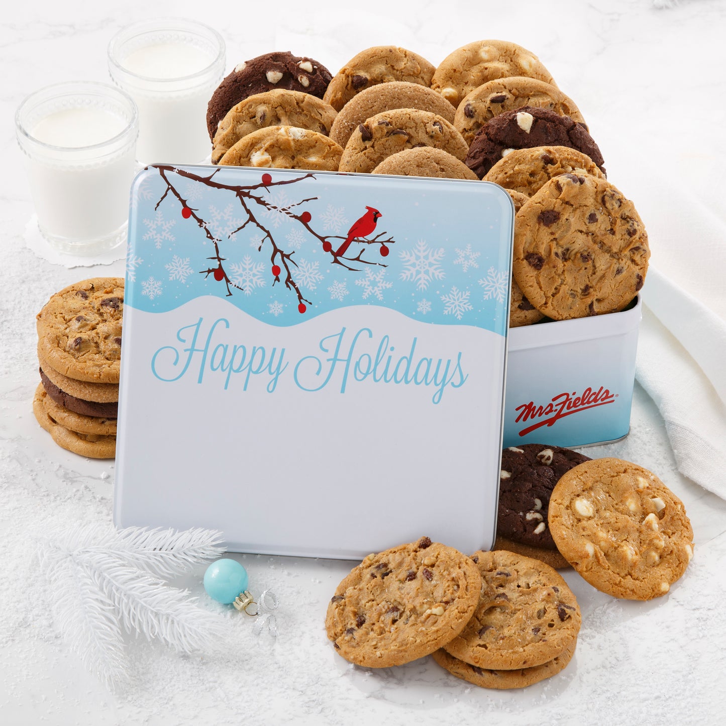 An outdoor winter scene with a red cardinal as decoration on a gift tin that is filled with an assortment of original cookies.