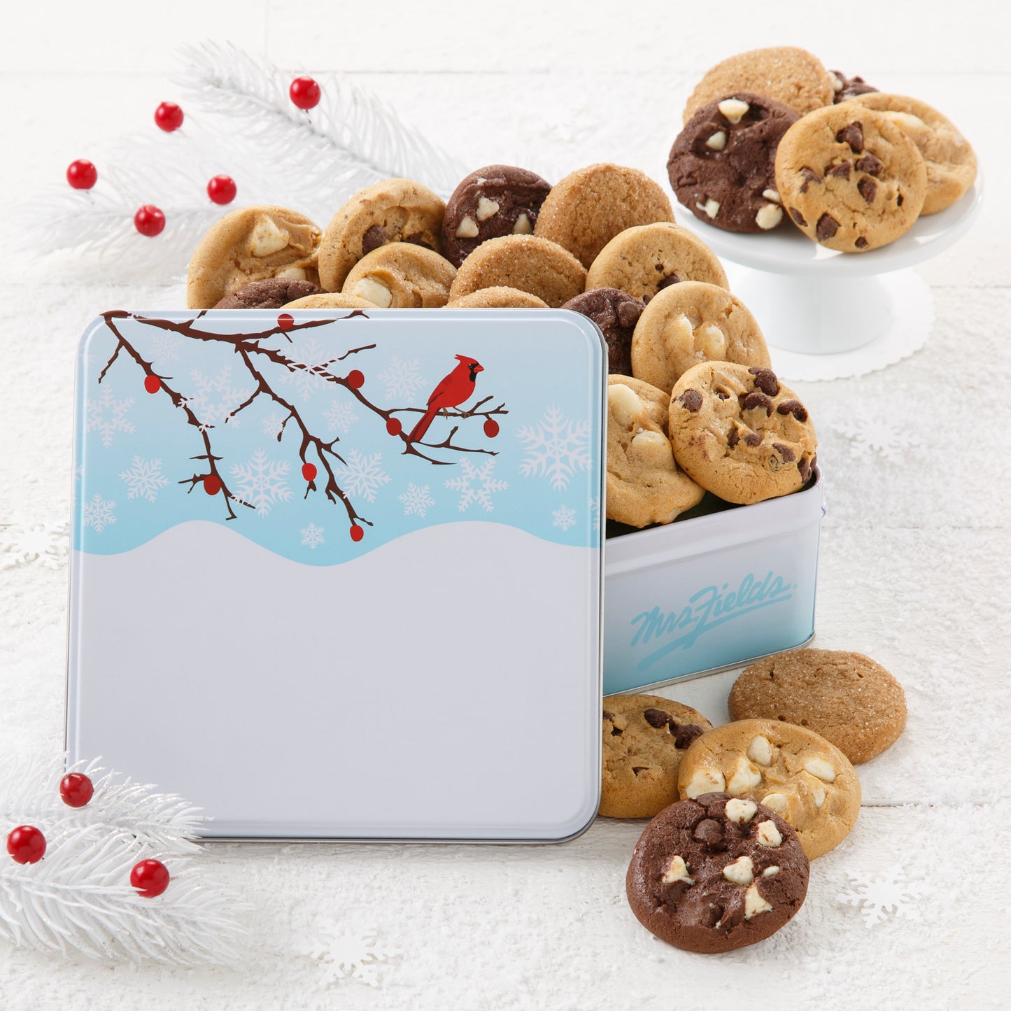 An outdoor winter scene with a red cardinal as decoration on a gift tin that is filled with an assortment of Nibblers®