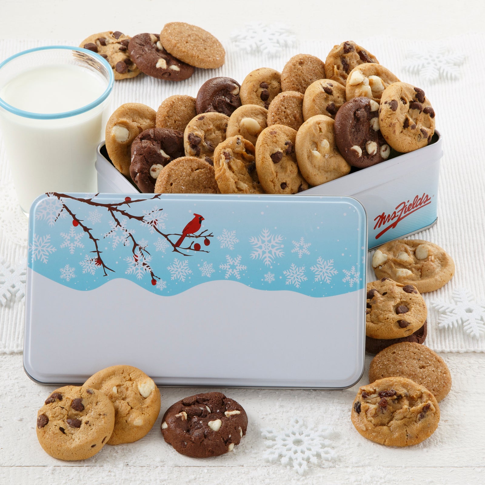 An outdoor winter scene with a red cardinal as decoration on a gift tin that is filled with an assortment of Nibblers®
