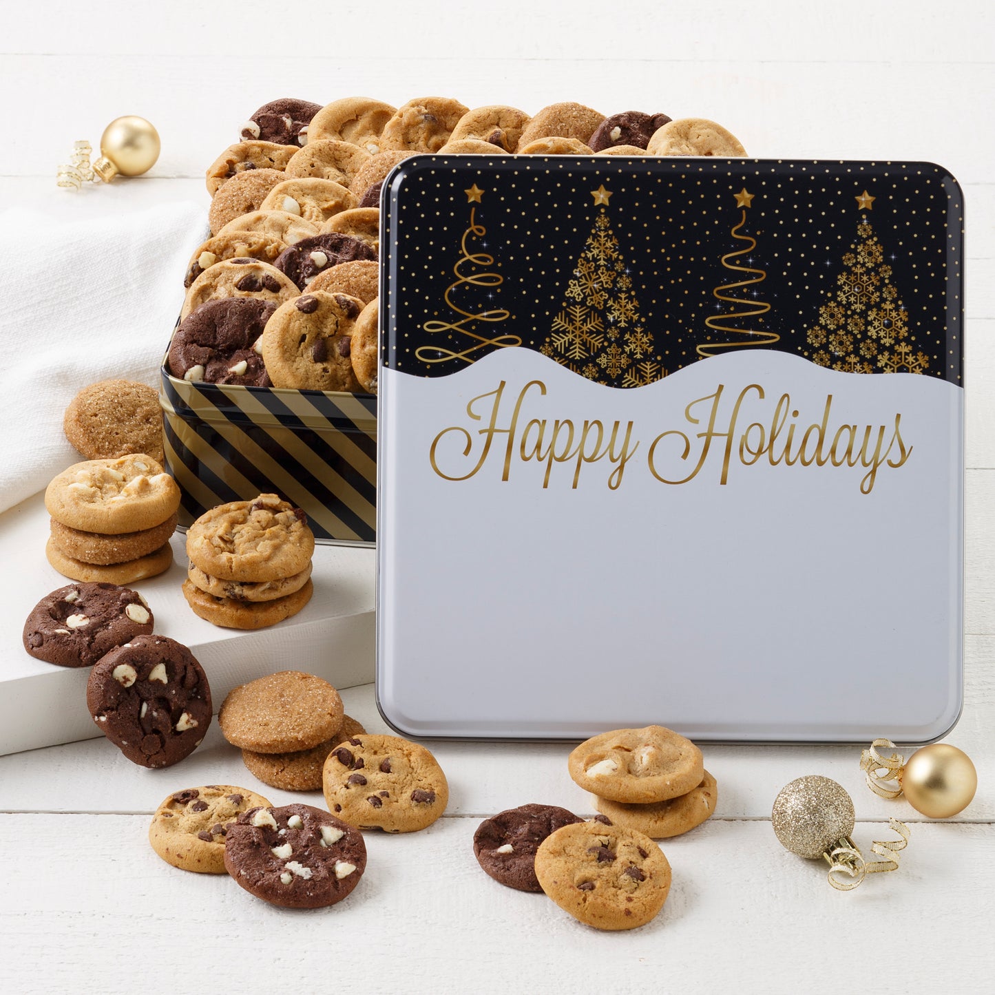 A Happy Holidays black and gold tin decorated with Christmas trees and filled with Nibblers®