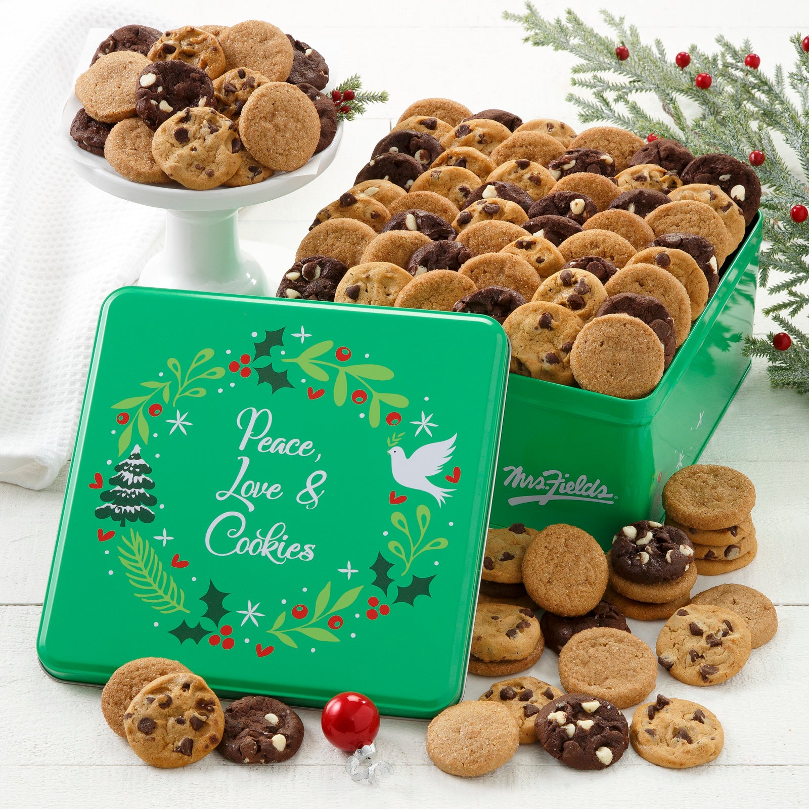Green Peace, Love, & Cookies tin decorated with a holiday wreath and filled with an assortment of no-nut Nibblers®