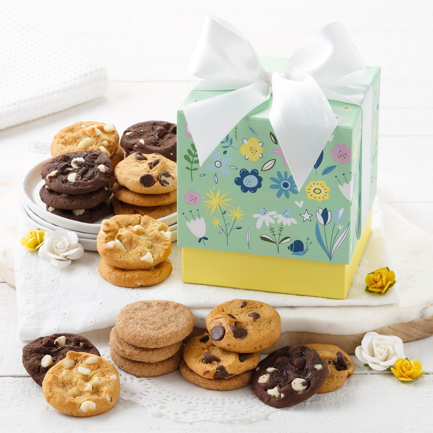 A spring themed light green and yellow mini gift box surrounded by an assortment of nibblers