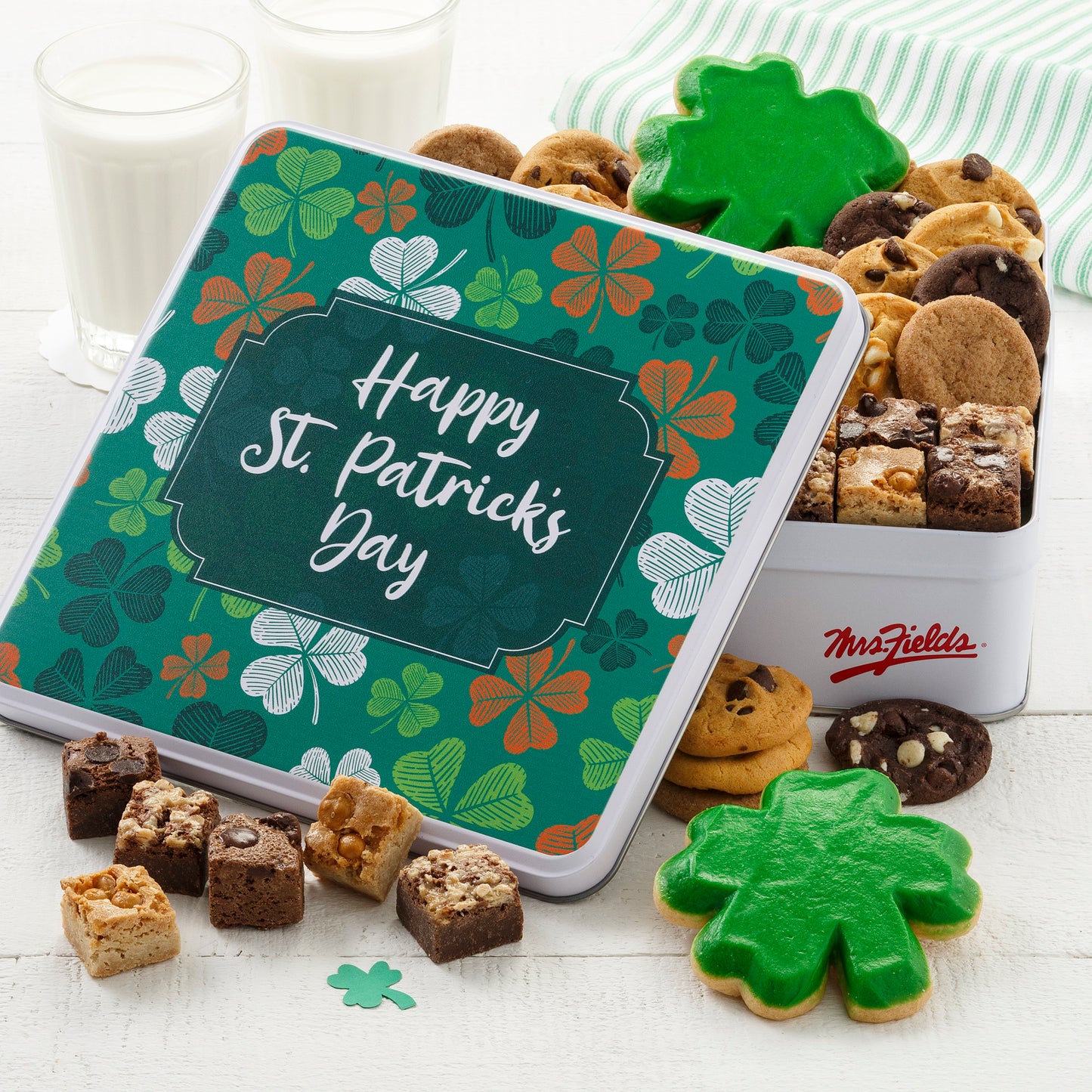 A Happy St. Patrick's Day gift tin decorated with clovers and filled with an assortment of nibblers, brownie bites, and two shamrock frosted cookies